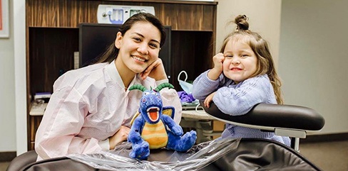 Smiling team member and child in dental exam room
