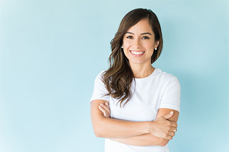 Woman in white shirt smiling with arms folded