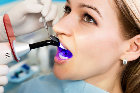 Close up of female patient having tooth-colored filling hardened in place