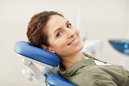 Smiling female patient leaning back in dental chair