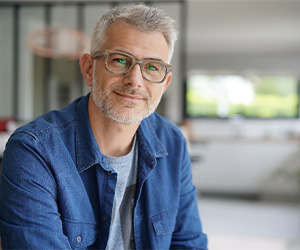 Smiling man with glasses and denim shirt